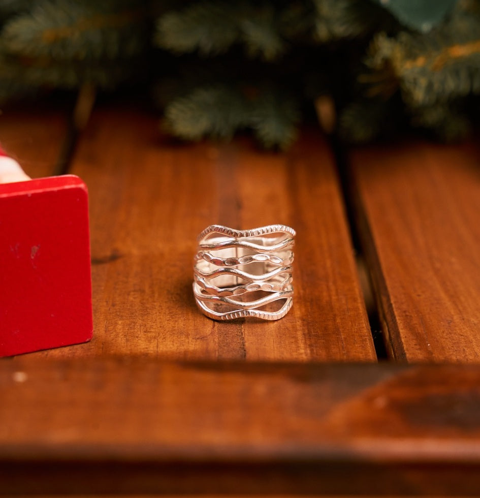Onda Ring in pure silver showing layered wavy bands in mixed textures.