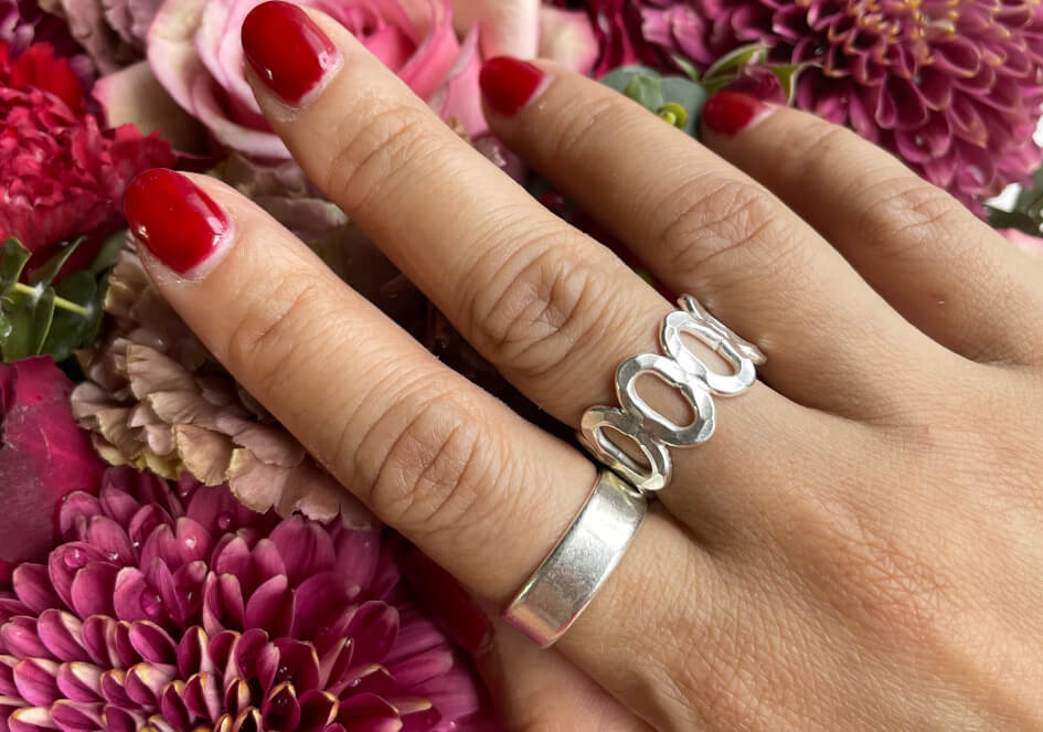 Model wearing a multi-circle adjustable silver ring from Hill to Street over flower background