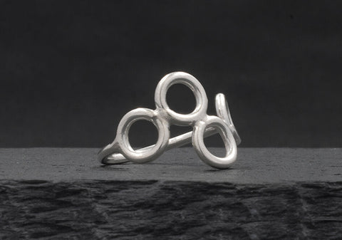 Multi-circle silver ring from Hill to Street seating on a dark grey stone over black background
