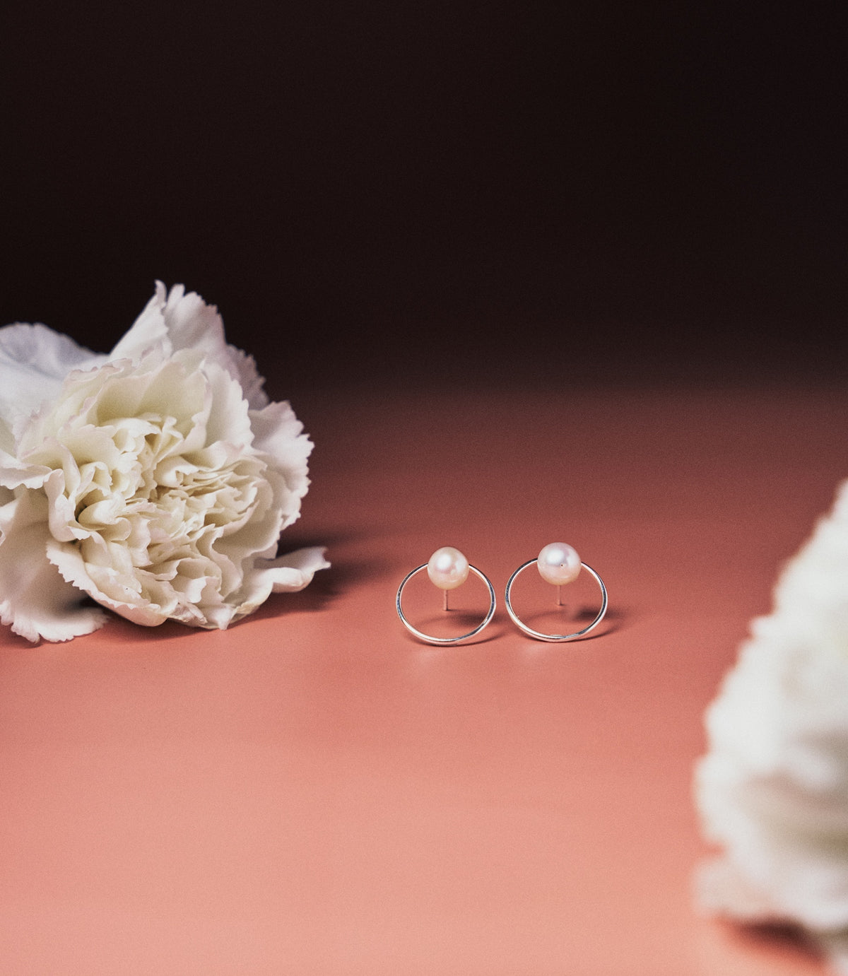 The Elina Pearl Earrings in 925 sterling silver featuring luminous pearl studs within a delicate circular frame.